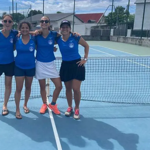 Quatre joueuses de l'équipe féminine du club posent ensemble au filet après un match.
